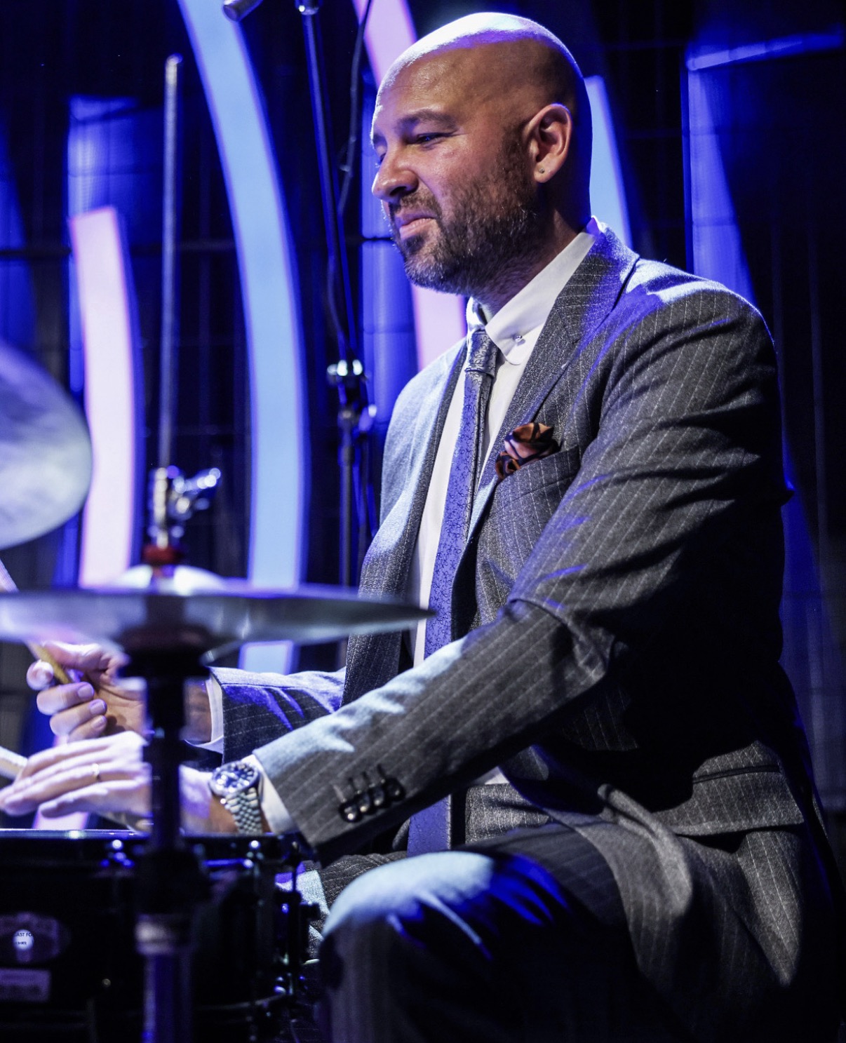 Ferit Odman performing at the drums wearing a tailored suit